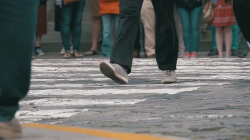 Pés de pessoas da multidão andando na passagem de pedestres em câmera lenta