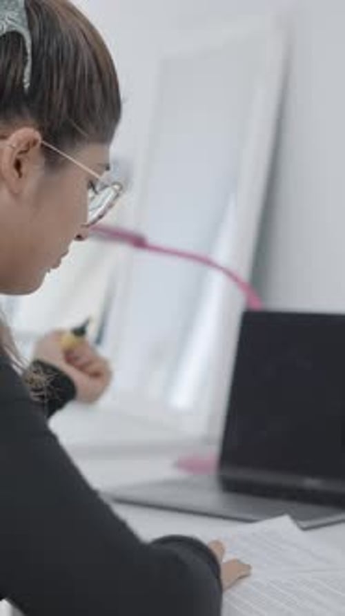 A Young Student Sitting at a Table Snd Studying She Takes Out a Highlighter From Her Bag and Starts