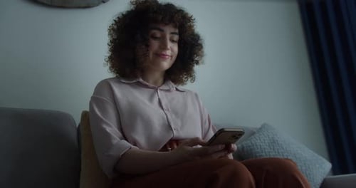 Brunet Curly Hair Smiling Woman Texting Telephone at Living Room Zoom on Positive Happy Woman