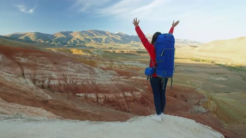 Woman Hiker Wih Big Backpack Enjoying View of Mountain Summit with Raising Her Arms Up Into the Sky