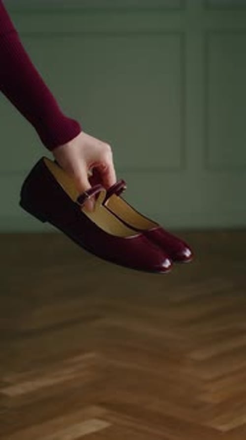 Woman Holds Elegant Patent Leather Shoes Indoors