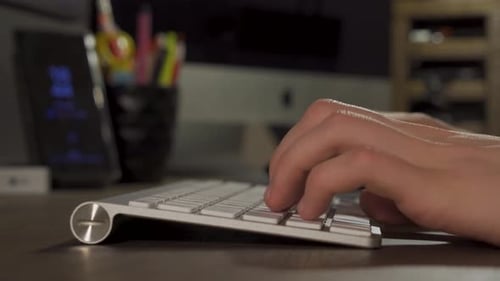 Hands Typing On A Slim White Computer Keyboard On The Table - closeup shot