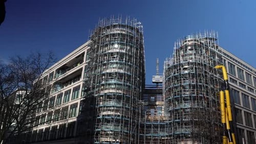 Moderno edificio de oficinas en construcción con andamios en un entorno urbano