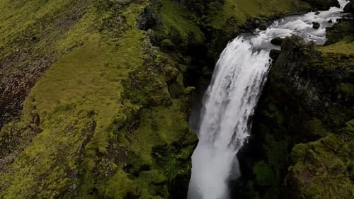 Big waterfall hidden in the middle of the mountains near Skogafoss, in Iceland. Aerial spinning to t