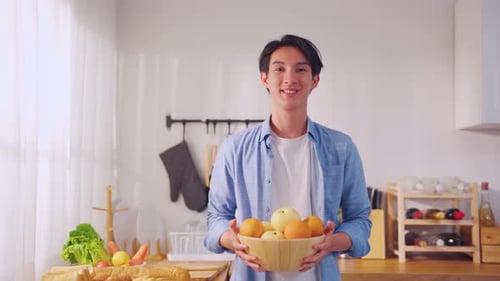 Portrait of Asian handsome male hold fruit bowl and looking at camera.