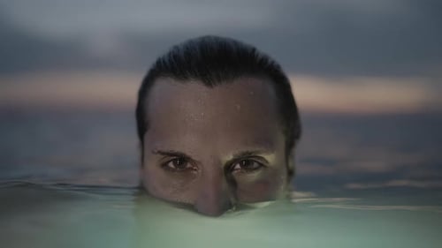Man's Face Emerging from Ocean Water at Sunset