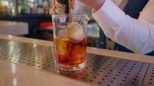 Bartender Mixing Cocktail Drink in Glass with Ice
