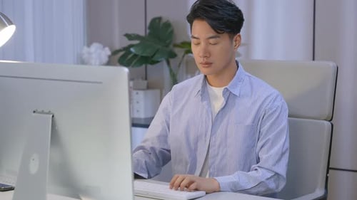 Businessman working overtime hands typing on a keyboard at desk during late hours at night in an off