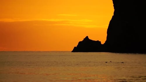 A Red Burning Sunset Over the Sea with Rocky Volcanic Cliff