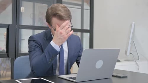 Stressed Businessman Working on Laptop in Office