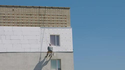 Construction Worker on Tall Building Facade