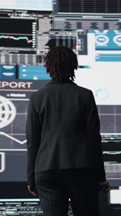 Vertical Video Management Executive Comparing Company Metrics on Digital Videowall