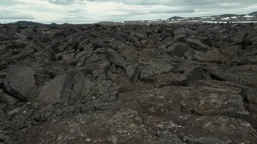 Flying above a huge Field of Stones with Mountains in the Background