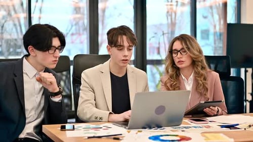 Business meeting in an office, female team leader and two young workers discussing business affairs