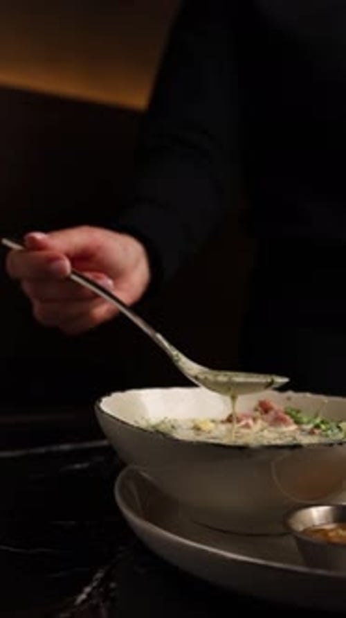 Hand stirs a bowl of soup in restaurant