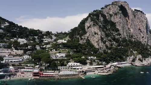 Wide drone shot of Capri, Italy's tourist-focused shoreline.