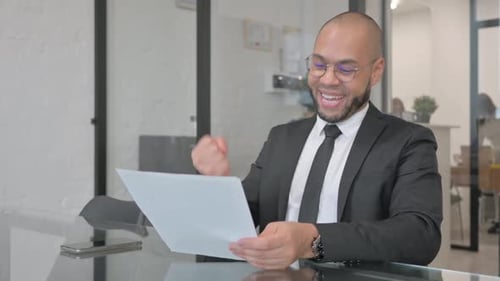 Excited Businessman Celebrates Reading Good News in Office