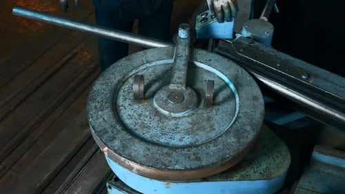 Un trabajador trabaja en una máquina dobladora de tubos en una planta siderúrgica