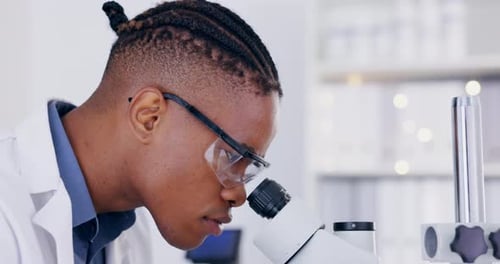 Young Adult Scientist Using Microscope in Lab