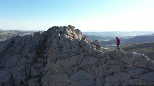 Man Climbs Rocky Mountain Ridge on Sunny Day