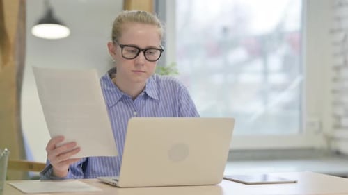 Young Woman Working with Laptop and Documents