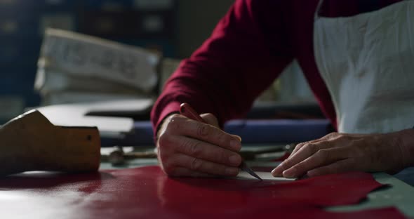 Close up of shoemaker who marks a leather to cut it and making some ...