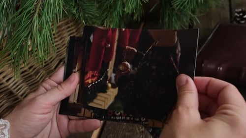 Mujer mira fotos navideñas impresas para álbum familiar