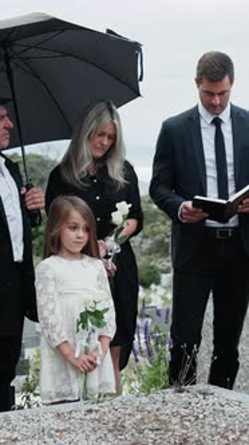 Family, tombstone and gathering with holy bible at funeral for grief or condolences in cemetery