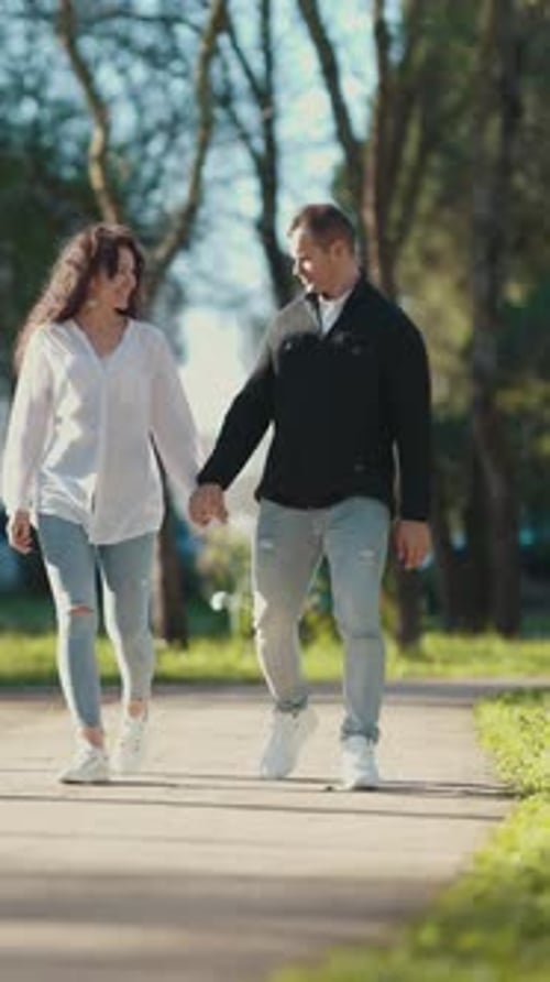 Young Couple Holding Hands While Walking in a Park