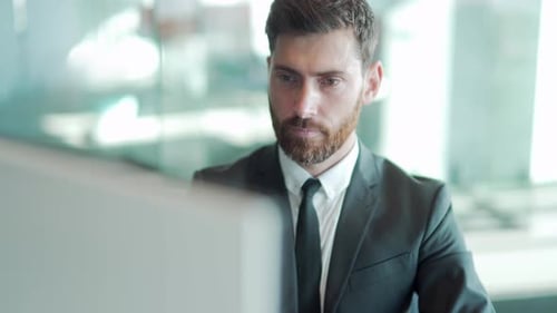 Portrait thoughtful male businessman working on pc computer at a modern office desk. Confident Focus