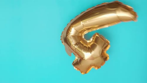Golden Balloon in the Shape of Four Flies and Falls on Blue Surface at Birthday