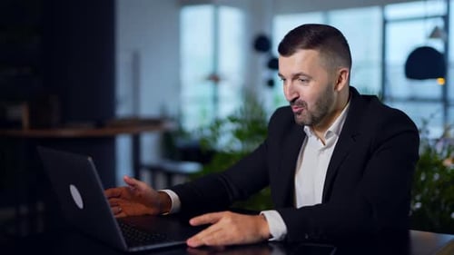 Man Communicating Over Laptop in Office Setting