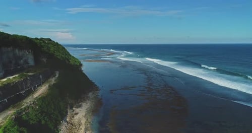 Wellen brechen an der Küste von Bali, Indonesien, mit Klippen und Vegetation