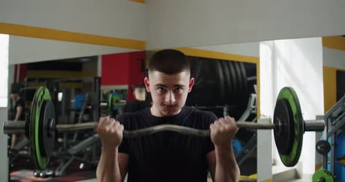 Man Doing Bicep Curls with Barbell at Gym