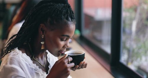 Coffee shop, happy and black woman by window with drink for relaxing, calm and breakfast in cafe
