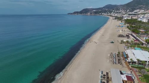 Luftbild eines atemberaubenden weißen Sandstrandes, der auf das azurblaue Meer trifft, während sanfte Wellen darauf rollen