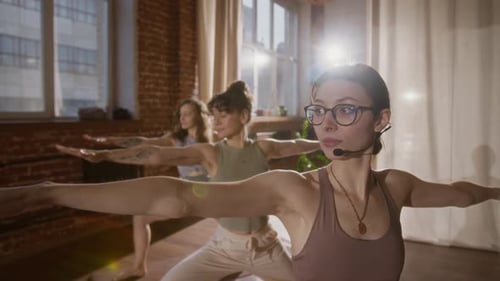 Female Yoga Teacher Instructing Class in Warrior and Triangle Asanas