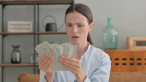 Portrait of Upset Young Woman Counting Money at Home