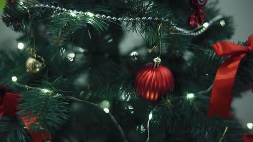 Decorating a Christmas Tree with Red Ornaments and Green Garlands in a Cozy Room During the Holiday