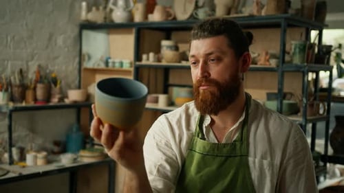 Bearded Potter Examining Handcrafted Ceramic Cup in Studio