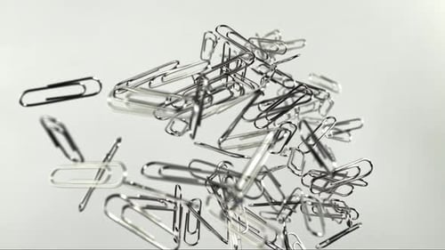 Shiny Silver Paperclips Floating and Falling on Surface