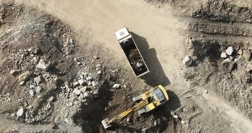 Industrial Mine Excavators are Digging the Soil in the Construction Site and Loading Trucks