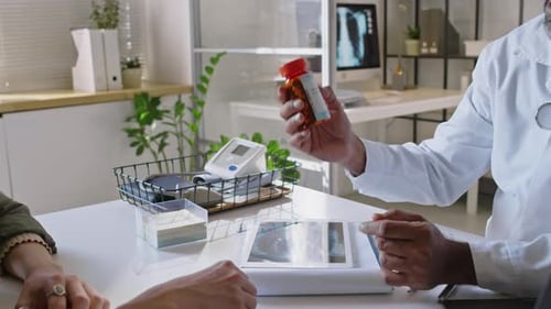 Doctor Hands Medication Bottle to Patient in Office