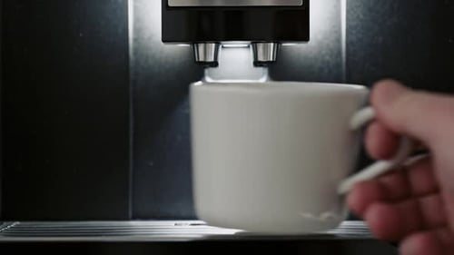 Person Placing a Cup Onto an Espresso Machine Close Up
