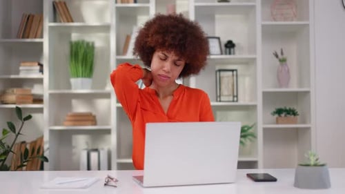Woman Massages Stiff Neck While Using Laptop