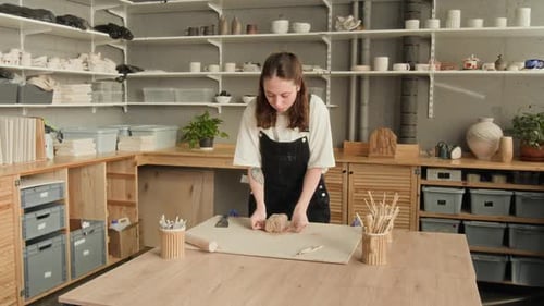Woman Cutting Pieces of Clay with String in Workshop