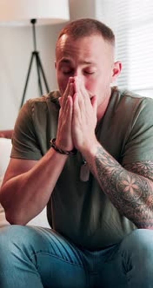 Man Sitting With Hands Clasped Near Face Indoors