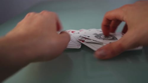 Zwei Hände nehmen ein Kartenspiel von einem Tisch auf, Nahaufnahme