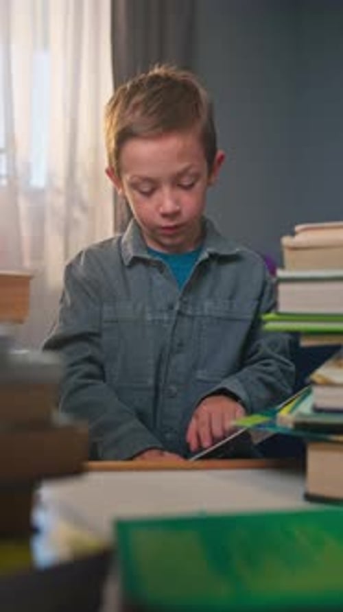 Focused Boy Reading Books at Desk