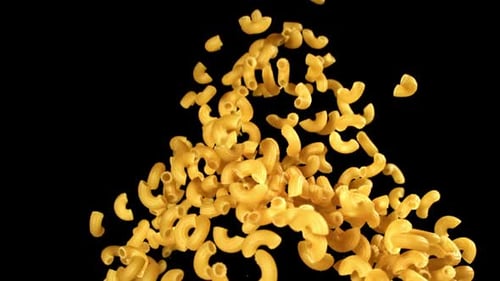 Delicious elbow macaroni falling on a black backdrop